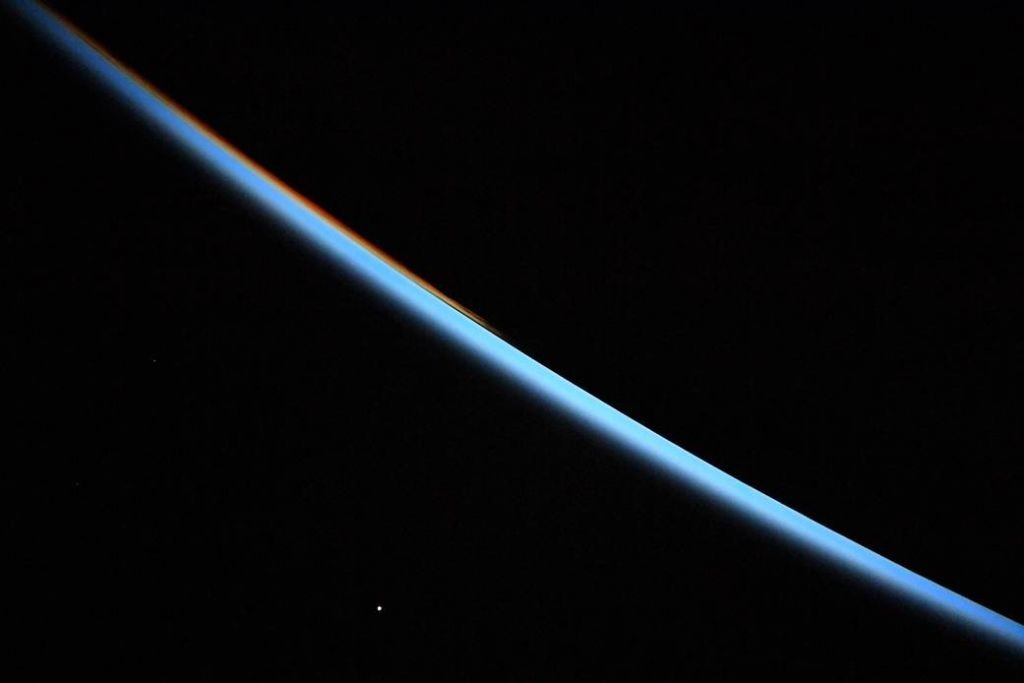 Venus rises in the sky as the sun rises from behind the earth